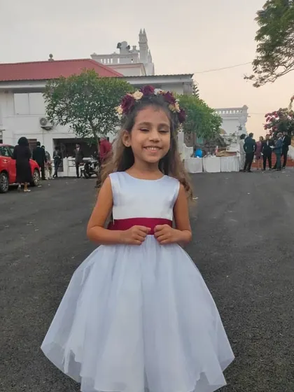 Ready for a special occasion in this classic white A-line dress. The simple silhouette is accented with a contrasting maroon sash, making it a versatile and elegant choice for a young wedding guest or partygoer.