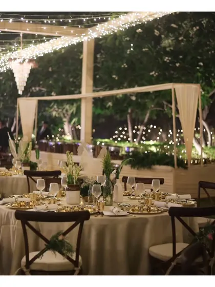 An elegantly set table at an outdoor event, with fairy lights creating a magical backdrop for a memorable dining experience.
