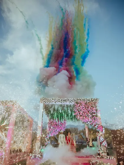 A spectacular Jaimala ceremony, where the sky erupts in a rainbow of colored smoke, creating a truly unforgettable and vibrant moment for the couple.