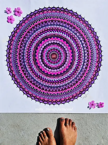 The large magenta mandala laid flat, giving a sense of its scale next to my feet. The sunlight brings out the different shades of pink and purple.