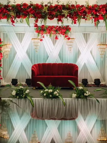 The full view of the striking red and white wedding stage, with its reflection on the glossy floor adding to the glamour.