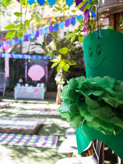 A glimpse of the party atmosphere from afar, showing the colorful decorations and outdoor setup with picnic mats ready for the little guests. I ensure every corner of the venue feels festive.