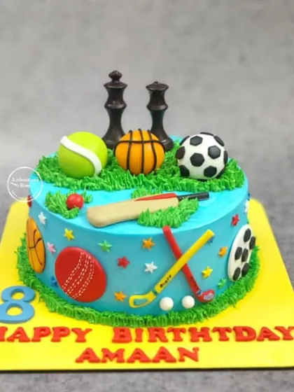 A multi-sport theme cake for an all-around athlete. This cake is covered in edible sports equipment, including a cricket bat, soccer ball, basketball, tennis ball, and chess pieces.