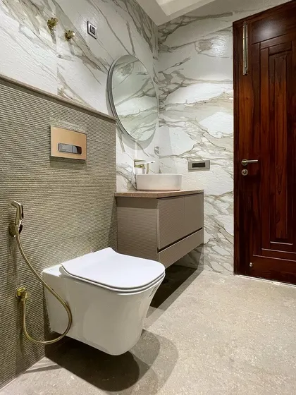 We used a combination of textures and tones in this bathroom. The walls are clad in a beautiful marble-look tile, while the area behind the toilet features a grooved stone tile. Brushed gold fixtures add a final touch of luxury.