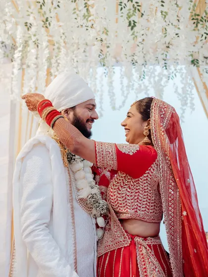 A candid, happy moment during the Jaimala ceremony, capturing the bride's excitement as she garlands the groom.