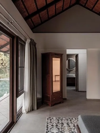 The master bedroom features large glass doors that slide open to the infinity pool and deck. The room is designed to feel like a private pavilion, with a direct connection to the stunning landscape.