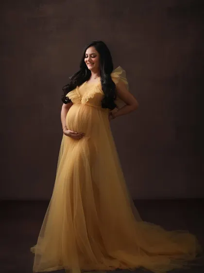 A moment of pure happiness. The mom-to-be's joyful smile and the warm, golden tones of the gown create a radiant and beautiful solo portrait.