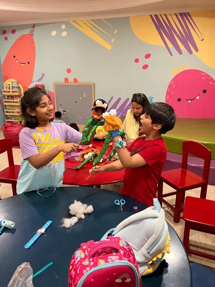 Look at the teamwork! Children collaborate to bring their handmade puppets to life, learning to share ideas and create a story together.
