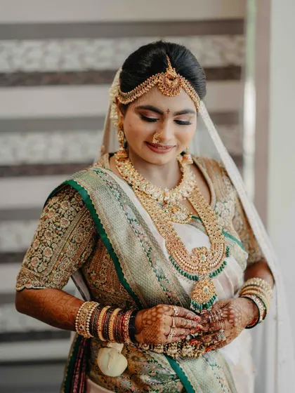 Another beautiful portrait of our bride, her smile radiating happiness. The rich, artisanal grandeur of her embroidered blouse is on full display, a true heirloom piece for her special day.