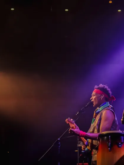 David Walters sings passionately, his guitar in hand, under dramatic stage lighting. This image captures the raw energy and musical talent showcased at our events.