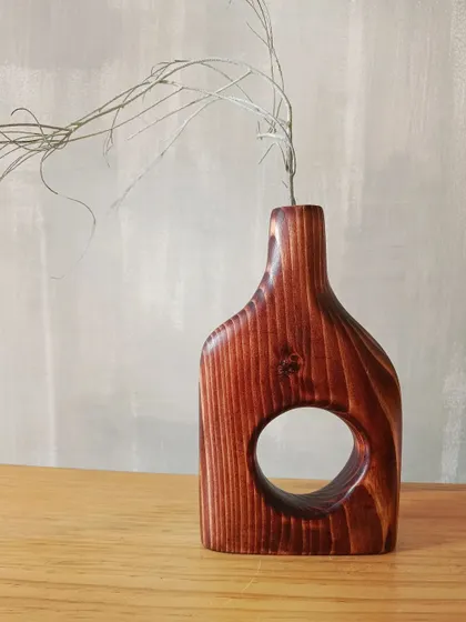 Our hand-carved wooden vase, styled with a single dried stem. Its minimalist and organic shape brings a sense of calm and nature indoors.