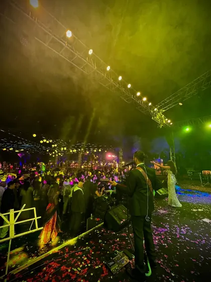 A wide shot from the stage, looking out at a massive wedding crowd. The combination of stage lighting, smoke effects, and a high-energy audience creates a truly epic party atmosphere.