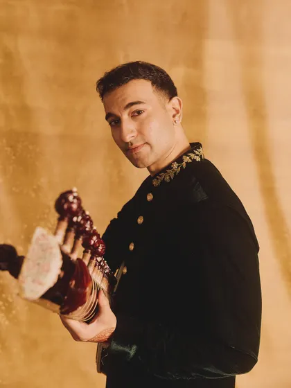 A confident look over the shoulder, holding the sitar.