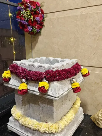 Even small elements like a traditional Tulsi Katte can be beautifully decorated with flower garlands to enhance the festive atmosphere during a home ceremony.