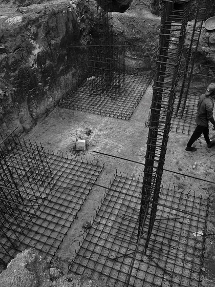 An overhead view of the rebar framework for a foundation. This intricate grid of steel is the unseen strength of the building, meticulously laid out by our construction team according to our structural plans.