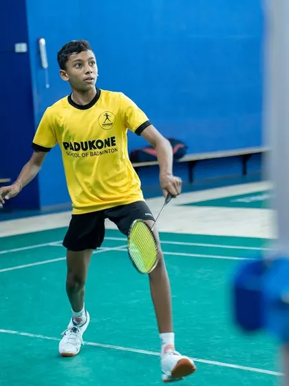 A young player in a Padukone academy jersey prepares to return a shot. Our tournaments provide crucial match practice for aspiring professionals.