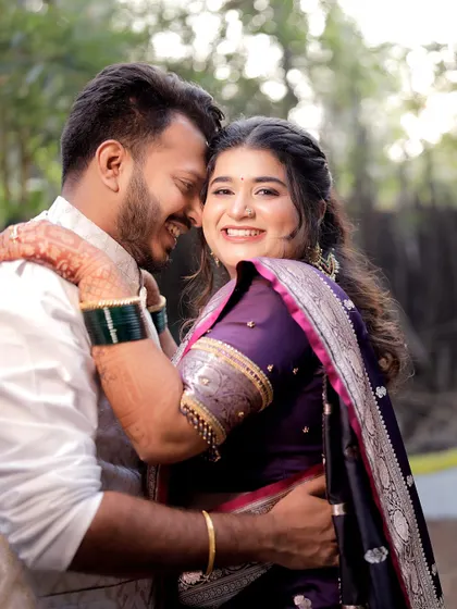 A candid shot filled with joy, showing the groom embracing his bride from behind. Her radiant smile captures the happiness of a Maharashtrian wedding ceremony.