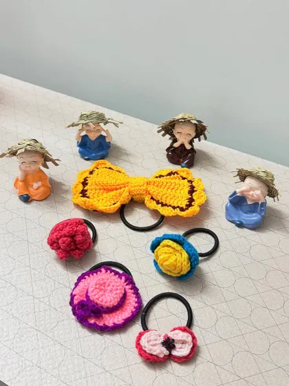 A collection of colorful, handmade crochet hair ties in various designs, including bows and flowers, perfect for adding a playful touch to any hairstyle.