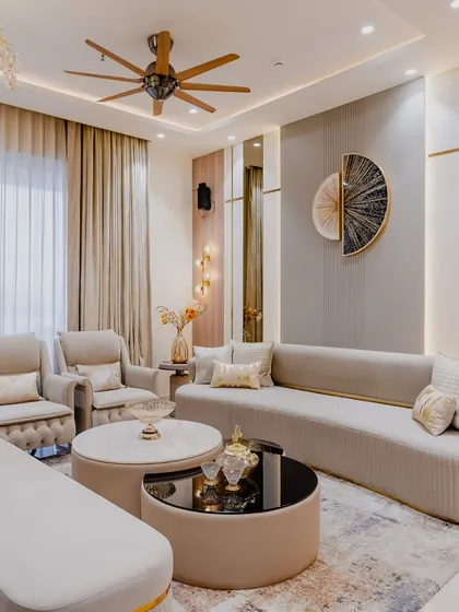 A closer look at the details that make this living room special. The combination of a curved sofa, armchairs, and a bench offers flexible seating, while the wall art and lighting act as focal points. This is a great example of a modern luxury interior design.