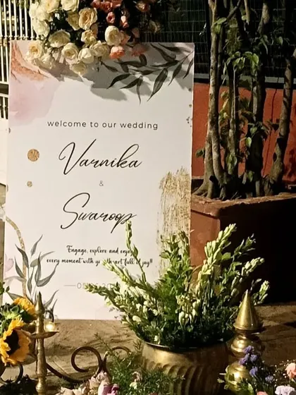 A personalized welcome sign for Varnika and Swarrop, elegantly displayed with traditional brass decor and floral arrangements.