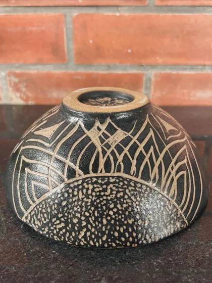 A stunning bowl with intricate sgraffito carving. The contrast between the black glaze and the raw clay body is so effective.