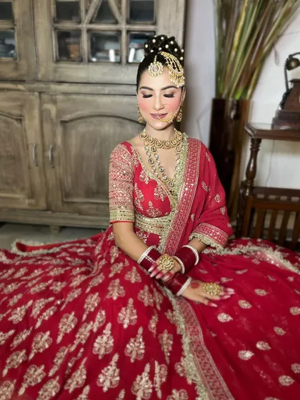 Another angle of the red and gold lehenga, showing the richness of the fabric and the consistency of the embroidery work.
