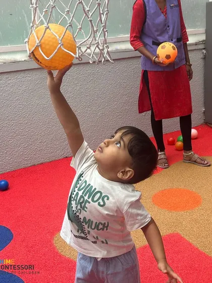 A child reaches for the basketball hoop, enjoying the physical challenges and fun of our indoor play space.