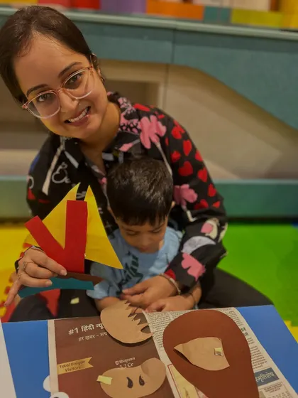 A mother smiles as she and her son hold up their finished crafts. The joy of completing a project together is a powerful confidence booster for toddlers.