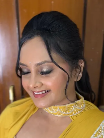A close-up of the modern hairstyle with face-framing tendrils, which perfectly complements the chic yellow saree.