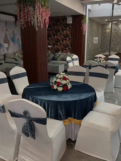 I also handle seating arrangements. This is a round table setup with a navy blue velvet tablecloth, white chair covers with matching sashes, and a floral centerpiece.
