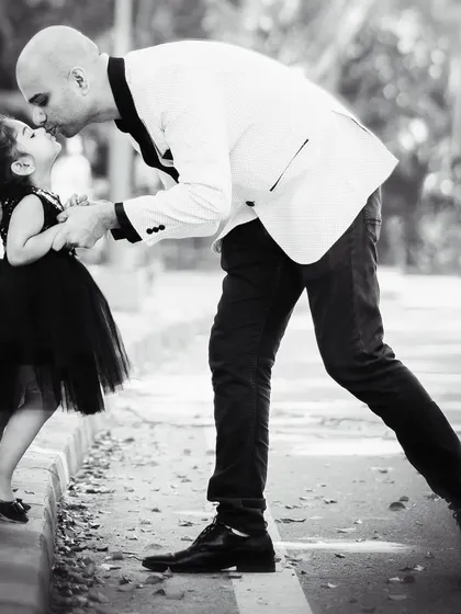 A timeless black and white photo capturing a tender moment between a father and his little girl. The gentle kiss on her forehead tells a story of protection and love. This image freezes a fleeting moment of connection that they will cherish forever.