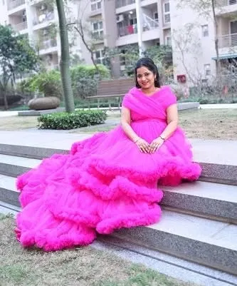 This bright pink ruffled gown with a long train looks stunning in an urban park setting. It's a fun and vibrant choice for a modern maternity shoot.