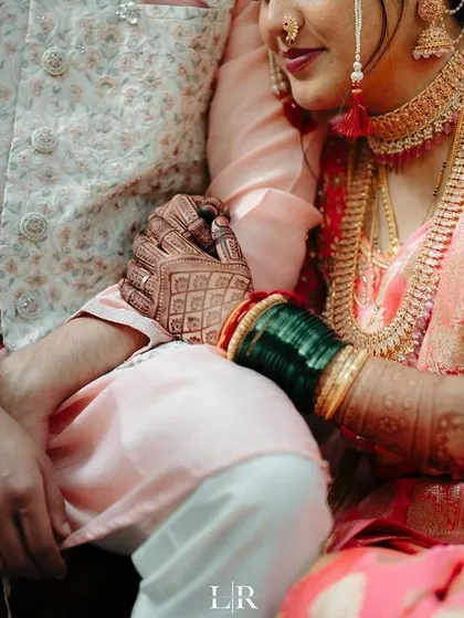 A close-up of the couple's hands, showing the intricate mehndi and the bride's traditional green bangles.