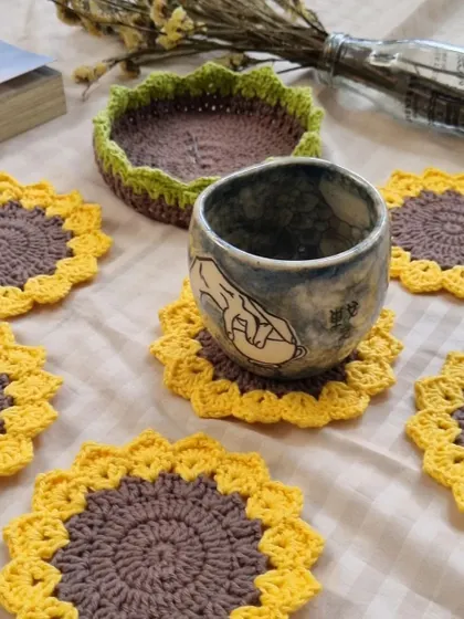 The full set of six sunflower coasters displayed with their handy storage basket. They are ready to bring a little sunshine to your tea time.