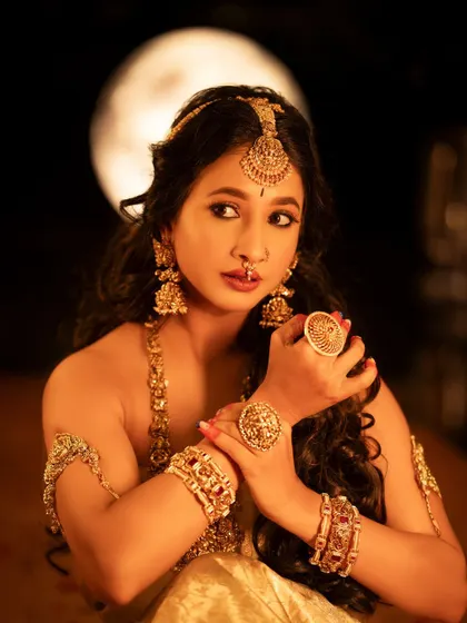 A close-up of Manvita Kamath, showcasing the intricate details of her jewelry and the soft, ethereal makeup look.