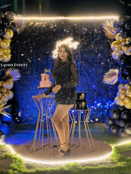The birthday girl looking glamorous in front of her black and gold sequin party backdrop.