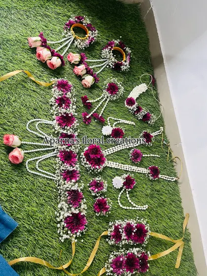 A grand floral set for a Haldi or baby shower. This design features deep magenta flowers, pink roses, and baby's breath, and includes a beautiful floral belt.