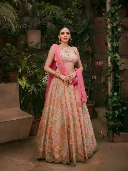 A full-length shot of a stunning Mehendi look with a colorful lehenga set against a lush green backdrop.