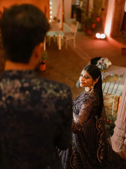 A beautiful over-the-shoulder shot during an evening function, capturing an intimate glance between the couple amidst the celebration.
