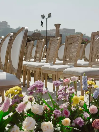 The elegant guest seating arranged for the ceremony. The clean lines of the chairs contrast beautifully with the organic, lush floral arrangements lining the aisle.