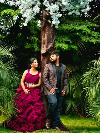 A quiet moment under a tree. The client's maroon ruffled gown provides a rich pop of color in this lush, green setting.