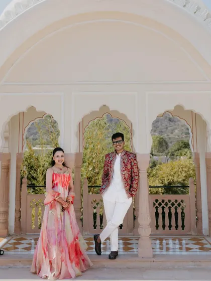 A stylish portrait of a couple posing in a palace corridor, their modern-traditional outfits contrasting beautifully with the classic architecture.