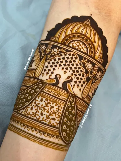 A close-up of the top portion of an arm band, featuring two peacocks in a decorative jharokha. The fine lines and patterns are a testament to skilled artistry.
