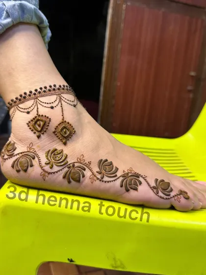 A close-up of a simple and elegant foot design. The floral trail and delicate anklet pattern are perfect for someone who wants a touch of henna without full coverage.