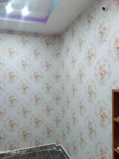 A room with a repeating floral medallion wallpaper.
