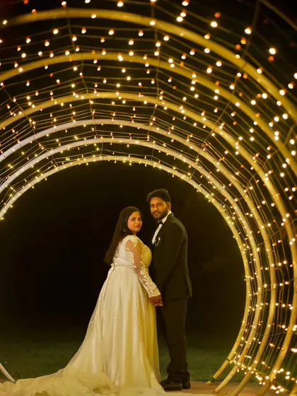A striking shot of a couple standing inside a tunnel of golden fairy lights, creating a magical and intimate pre-wedding portrait.