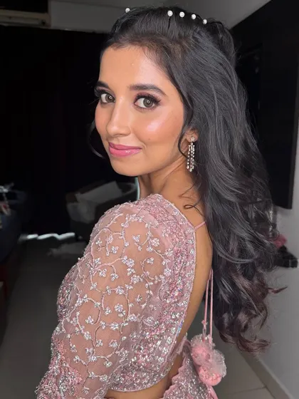 A pretty-in-pink Sangeet look, featuring soft makeup and a playful hairstyle with pearl details.