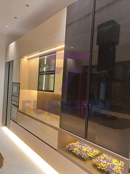 Here, the focus is on the tall unit with a smoked glass sliding door, which cleverly conceals appliances and storage. This feature helps maintain a clean, uncluttered look while keeping everything easily accessible.