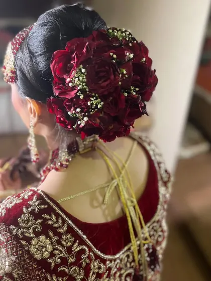 A bridal hairstyle needs to be beautiful from every angle. This classic bridal bun, decorated with fresh red roses and baby's breath, is a perfect example. It’s elegant, secure, and provides a perfect base for setting the dupatta.