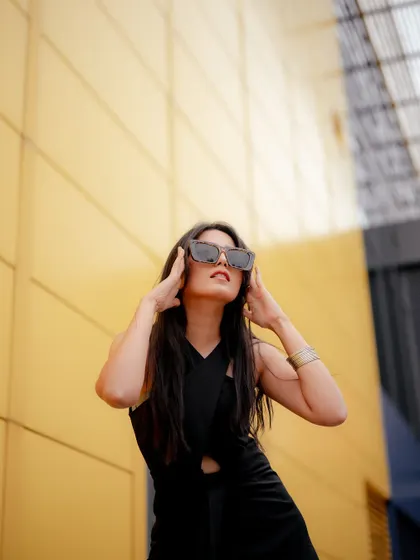 A low-angle shot against a bright yellow wall creates a bold, graphic look. This composition makes the model in the black dress appear powerful and is perfect for an eye-catching ad campaign.